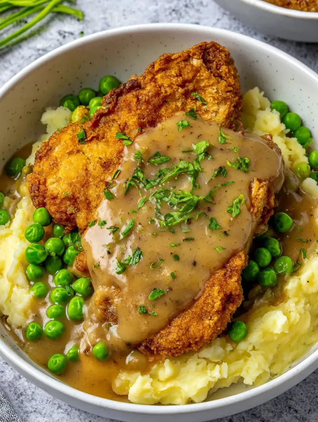 A bowl of food with chicken and peas.
