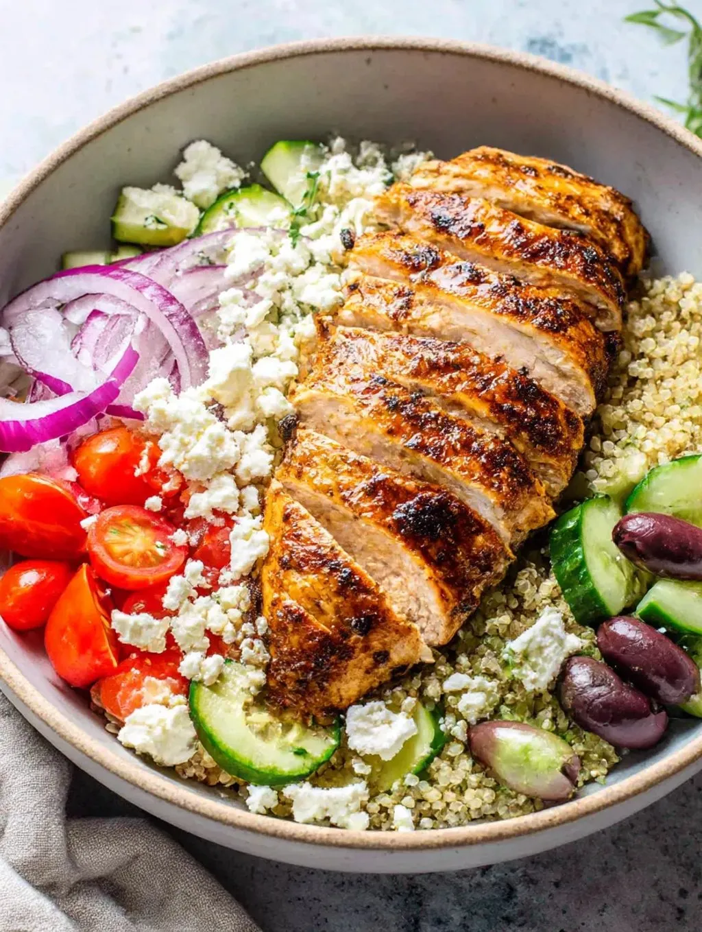 A Greek chicken quinoa bowl with vegetables.