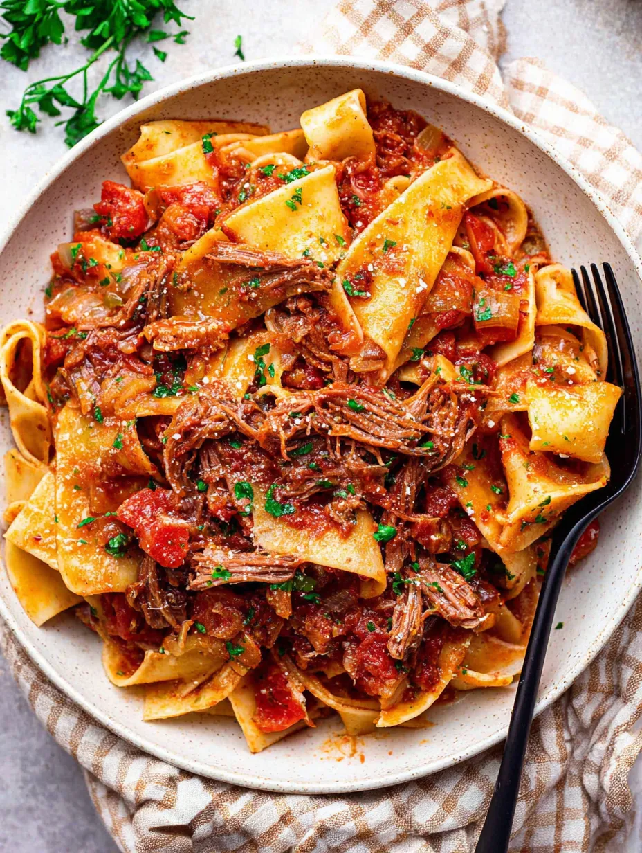 A plate of pasta with meat and tomatoes.
