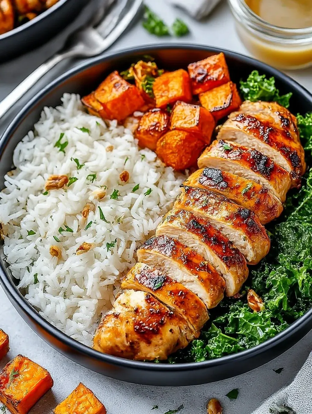 A bowl of food with chicken, sweet potatoes, kale, and rice.