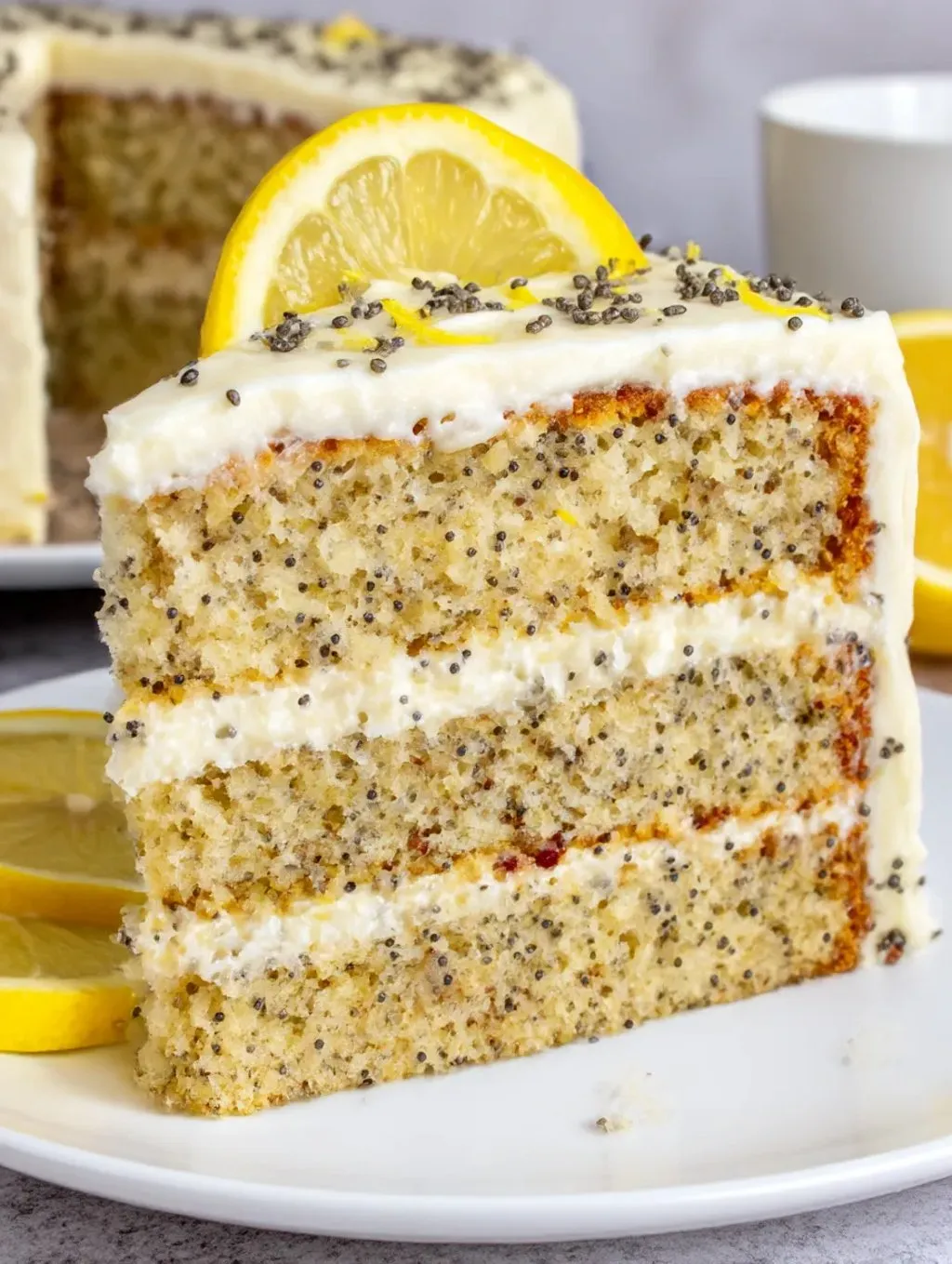 A slice of cake with lemon and poppy seeds on top.