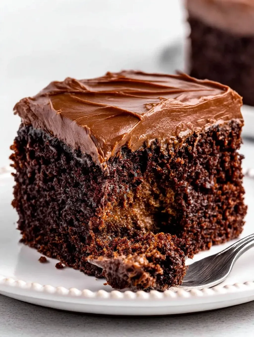 A slice of chocolate cake with chocolate frosting.
