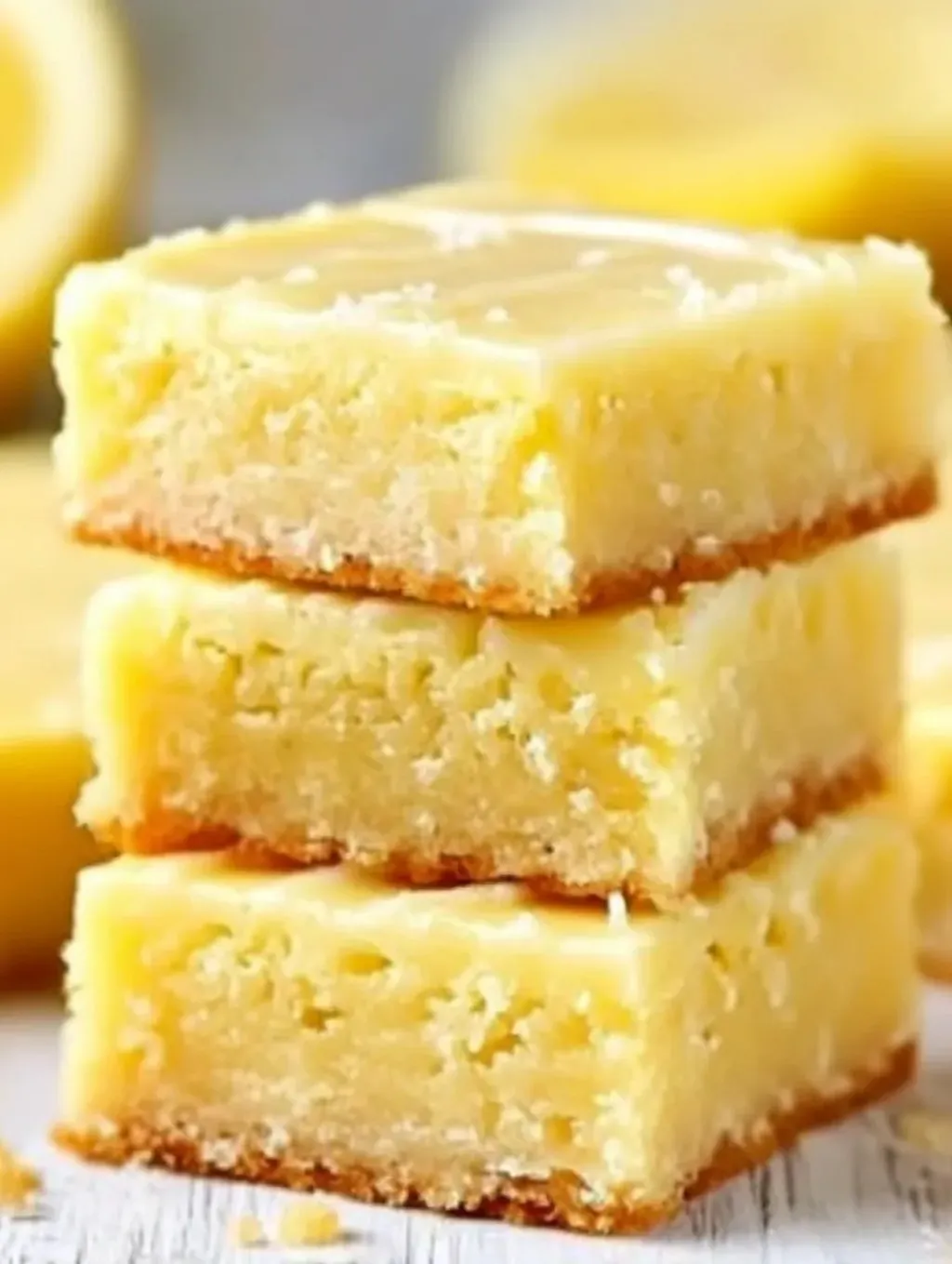 Three pieces of lemon brownies stacked on top of each other.