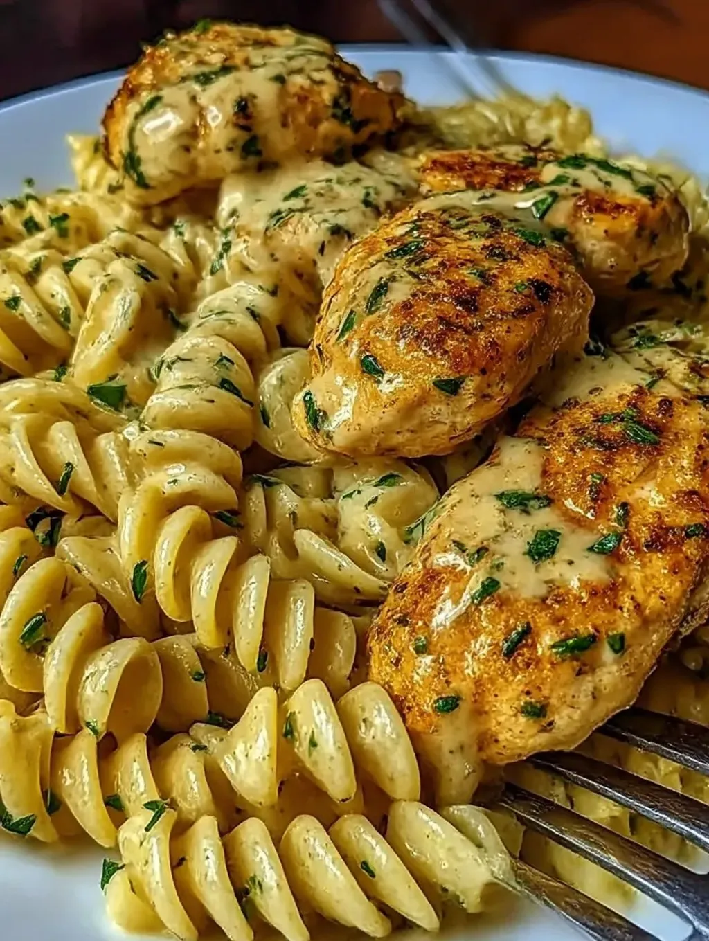 A plate of pasta with chicken and garlic sauce.