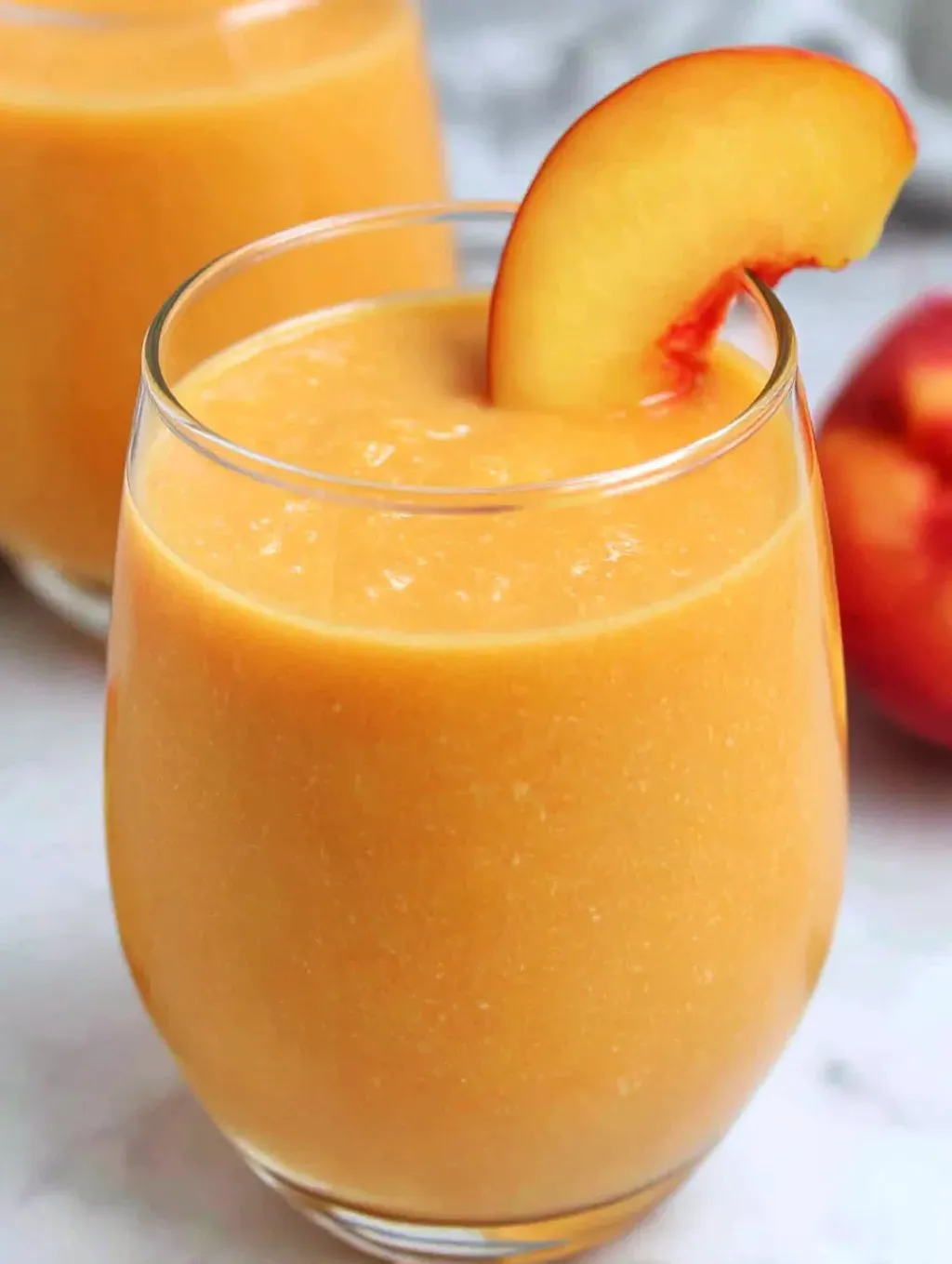 A glass of fresh peach blender juice.