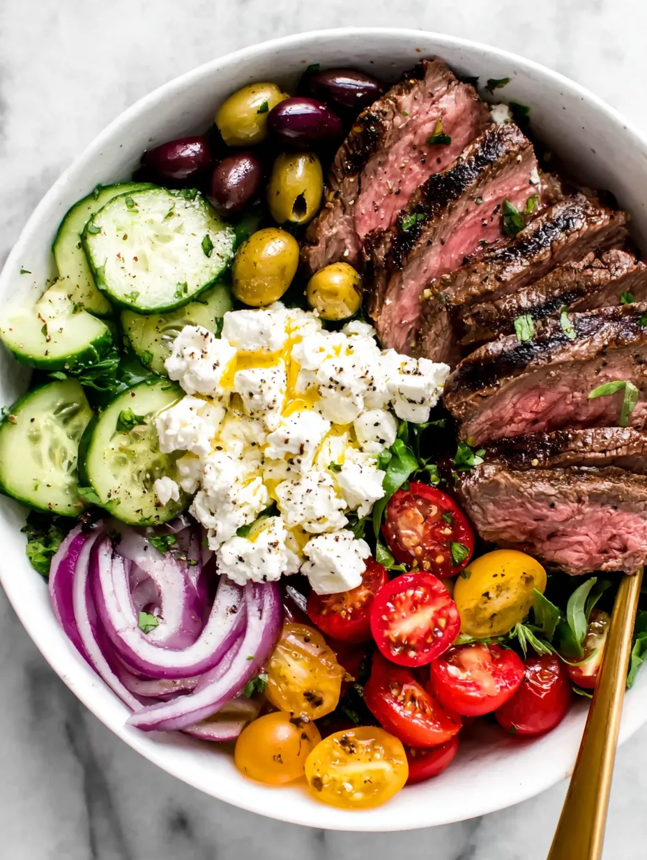 A bowl of food with meat, tomatoes, cucumbers, and cheese.