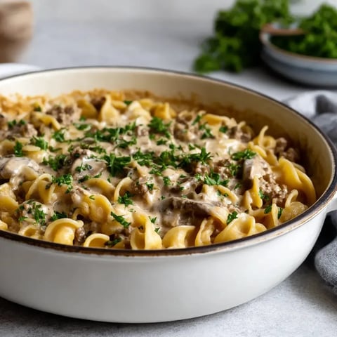 A bowl of beef stroganoff with noodles and herbs.