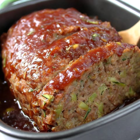 A meatloaf with zucchini in a pan.